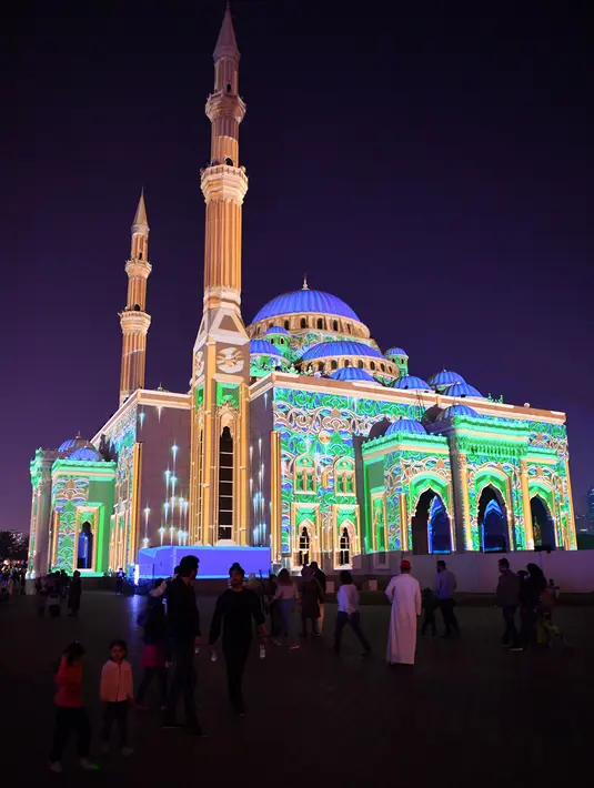Pengunjung berada di depan Masjid Al-Noor yang diterangi lampu warna-warni selama Festival Cahaya Sharjah di Uni Emirat Arab pada 7 Februari 2020. Festival yang sudah memasuki tahun kesepuluh ini selalu sukses memikat wisatawan lokal maupun asing. (Photo by GIUSEPPE CACACE / AFP)