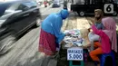 Seorang ibu ditemani anaknya melayani pembeli saat berjualan masker kain buatan rumahan di Jalan Raya Cinere-Depok, Limo, Depok, Rabu (8/4/2020). Dalam sehari ia  mampu menjual rata-rata 300 masker kain. (merdeka.com/Arie Basuki)