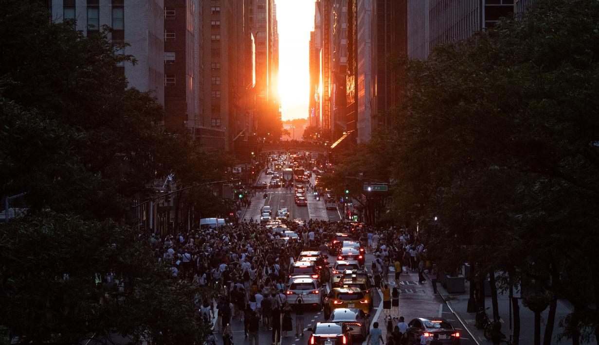 Matahari terbenam di Manhattan ketika fenomena "Manhattanhenge" di 42nd street, New York, Senin (11/7/2022). Manhattanhenge adalah keadaan dimana matahari terbenam tepat berada dalam garis lurus dengan jalanan Manhattan yang melintang dari timur ke barat. (Yuki IWAMURA / AFP)