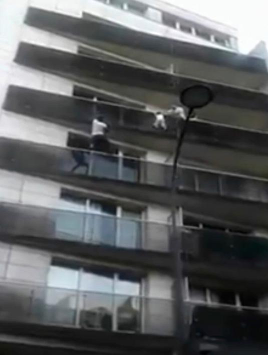 Momen ketika imigran asal Mali, Mamoudou Gassama menyelamatkan seorang balita yang nyaris jatuh dari balkon lantai empat sebuah apartemen di Paris, Prancis, Sabtu (26/5). (AP)