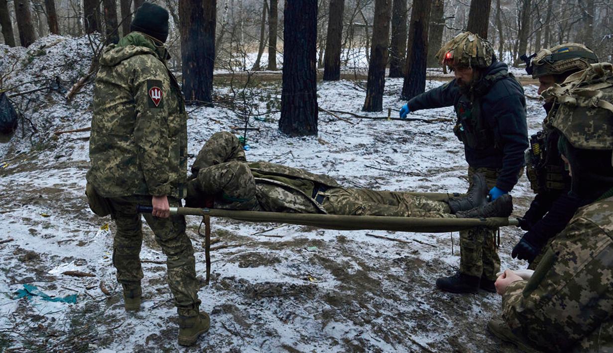 Petugas medis militer membawa tentara yang terluka ke kendaraan evakuasi dekat Kremenna di wilayah Luhansk, Ukraina, 16 Januari 2023. Hingga saat ini pejabat Ukraina menolak untuk mengonfirmasi jumlah korban dalam perangnya dengan Rusia, setelah ketua Komisi Uni Eropa pada akhir November 2022 lalu memperkirakan bahwa "lebih dari 20.000 warga sipil dan 100.000 tentara Ukraina telah tewas di Ukraina hingga saat ini." (AP Photo/LIBKOS)