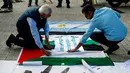 Aktivis pro-Palestina menempelkan jersey timnas Argentina yang bertuliskan ungkapan terima kasih dengan bendera nasional Palestina di Barcelona (6/6). (AFP Photo/Pau Barrena)