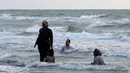 Warga Iran berenang saat sore hari di pantai di kota Laut Kaspia, Izadshahr, di provinsi Mazandaran utara (8/7/2019). Dalam Laut Kaspia terdapat banyak sturgeon, yang melahirkan telur yang diproses menjadi kaviar. (AFP Photo/Atta Kenare)