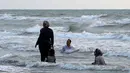 Warga Iran berenang saat sore hari di pantai di kota Laut Kaspia, Izadshahr, di provinsi Mazandaran utara (8/7/2019). Dalam Laut Kaspia terdapat banyak sturgeon, yang melahirkan telur yang diproses menjadi kaviar. (AFP Photo/Atta Kenare)