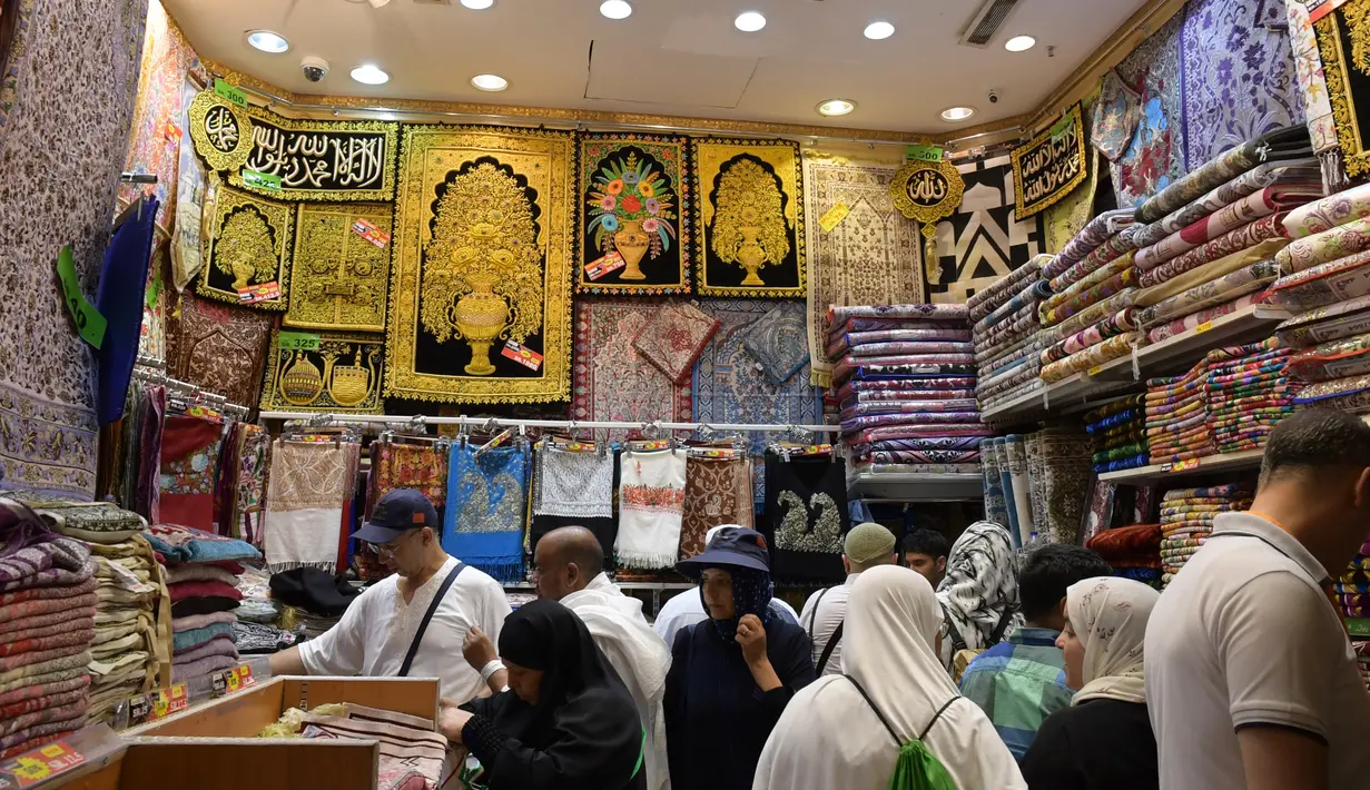 Jemaah haji memilih sajadah yang dipajang di sebuah toko di kota suci Makkah, Arab Saudi pada Selasa (6/8/2019). Puncak Ibadah haji masih beberapa hari lagi, namun jemaah sudah memborong aneka barang antara lain tasbih, baju, teko emas, kurma, sajadah, minyak wangi dan lainnya. (FETHI BELAID/AFP)