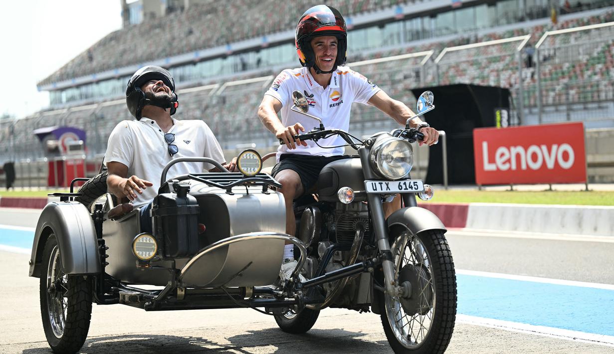 Pembalap Repsol Honda, Marc Marquez (kanan) dan mantan atlet kriket India, Suresh Raina mengendarai motor roda tiga di Sirkuit Buddh, New Delhi, India menjelang MotoGP India 2023 pada 21 September 2023. (AFP/Money Sharma)