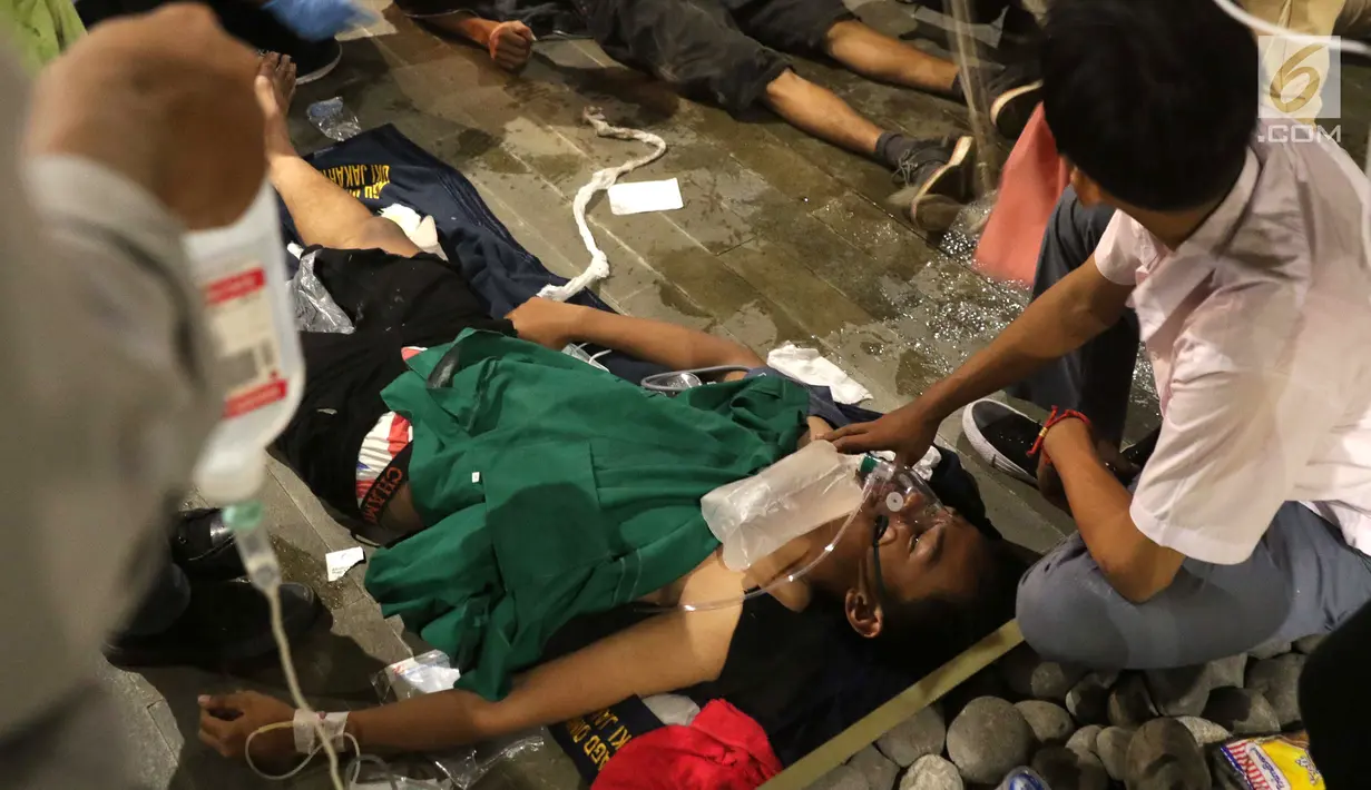 Seorang pria mendapat perawatan setelah menjadi korban dalam demonstrasi berujung ricuh di Pejompongan, Jakarta, Rabu (25/9/2019). Sebelumnya, ribuan pelajar yang melangsungkan demonstrasi di Gedung DPR terlibat bentrok dengan polisi. (Liputan6.com/Helmi Fithriansyah)