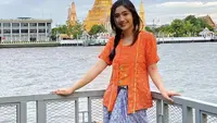 Berlibur ke Bangkok, Febby tampil mengenakan kebaya kutu baru warna orange dipadukan kain batik biru yang dijadikan skirt. [Instagram/@febbyrastanty]