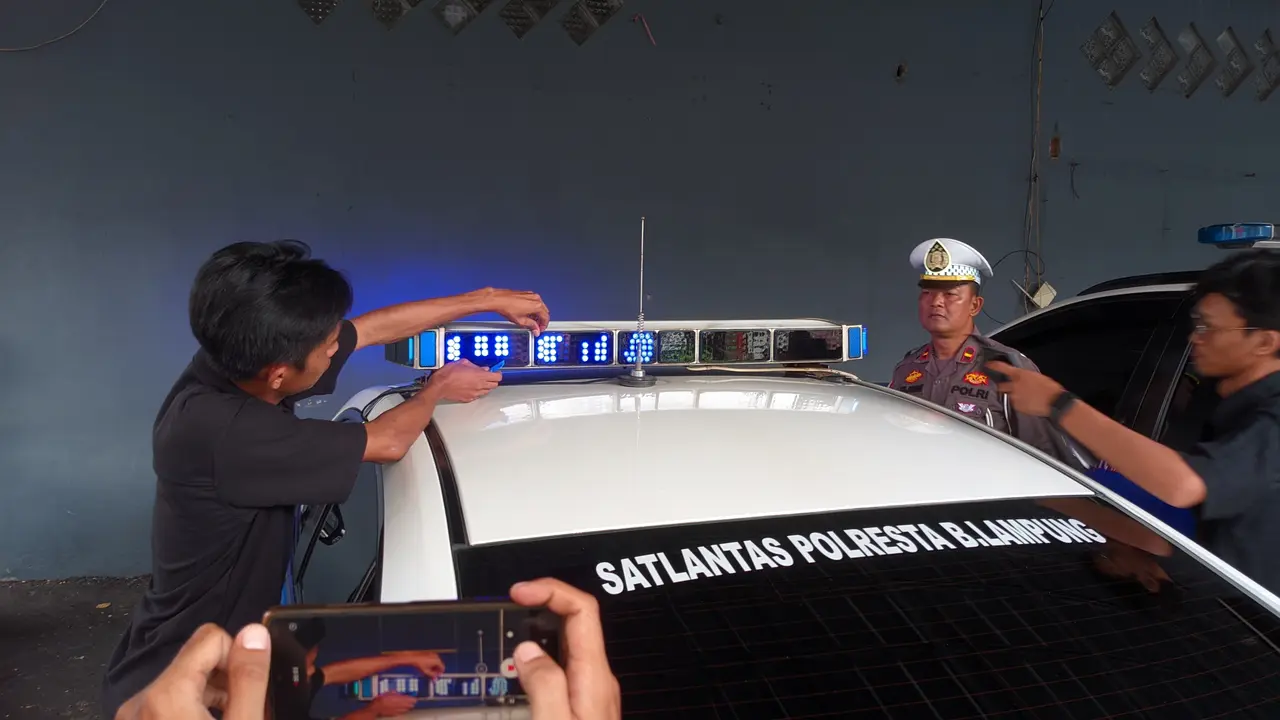 Pemasangan kaca film pada lampu rotator mobil Satlantas Polresta Bandar Lampung. Foto : (Liputan6.com/Ardi)