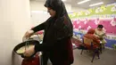 Lebih dari setengah juta warga terpaksa mengungsi setelah serangan Israel menghantam beberapa wilayah di Lebanon. Tampak dalam foto, seorang perempuan pengungsi yang tinggal bersama keluarganya di ruang kelas sekolah, setelah melarikan diri dari serangan udara Israel di pinggiran selatan Beirut, Lebanon, duduk untuk berbuka puasa bersama, pada 7 Maret 2026. (Ibrahim AMRO/AFP)