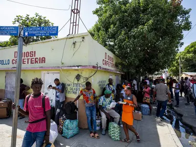 Para pembeli berdiri dengan tas berisi barang-barang yang mereka beli di Dajabón, Republik Dominika, sebelum melintasi perbatasan ke Haiti, Kamis, 14 September 2023. (AP Photo/Ricardo Hernández)