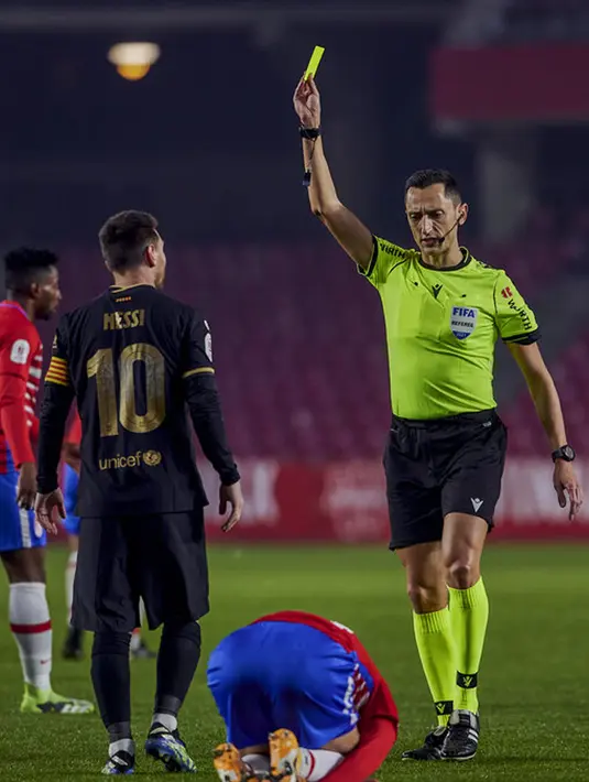Wasit Jose Marwa Sanchez Martinez menunjukkan kartu kuning kepada pemain Barcelona Lionel Messi saat melawan Granada pada pertandingan perempat final Copa del Rey di Stadion Los Carmenes, Granada, Spanyol, Rabu (3/2/2021). Barcelona mengalahkan Granada 5-3. (AP Photo)