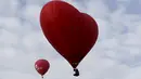 Sebuah balon udara panas berbentuk hati (kanan) terbang di langit selama Love Cup 2016 di Jekabpils, Latvia (14/2). Nikah massal yang diikuti oleh 50 pasangan ini menggelar akad di atas 27 balon udara. (REUTERS/Ints Kalnins)