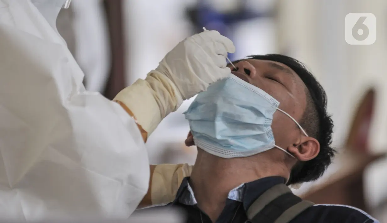 Petugas medis saat melakukan tes Covid-19 kepada salah satu warga di GOR Kecamatan Makasar, Jakarta Timur, Senin (17/5/2021). Hari ini tercatat sebanyak 71 warga yang diundang oleh RT di wilayah masing-masing menjalani tes Covid-19, baik tes antigen maupun PCR. (merdeka.com/Iqbal S Nugroho)