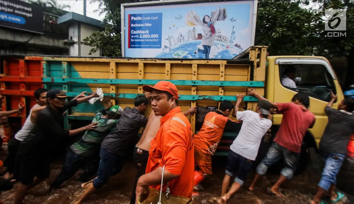Petugas dibantu warga mendorong truk yang mogok akibat terjebak banjir di terowongan Dukuh Atas, Jakarta, Senin (11/12). Akibat banjir tersebut, banyak kendaraan yang mogok, dan jalan tidak dapat diakses warga. (Liputan6.com/Faizal Fanani)