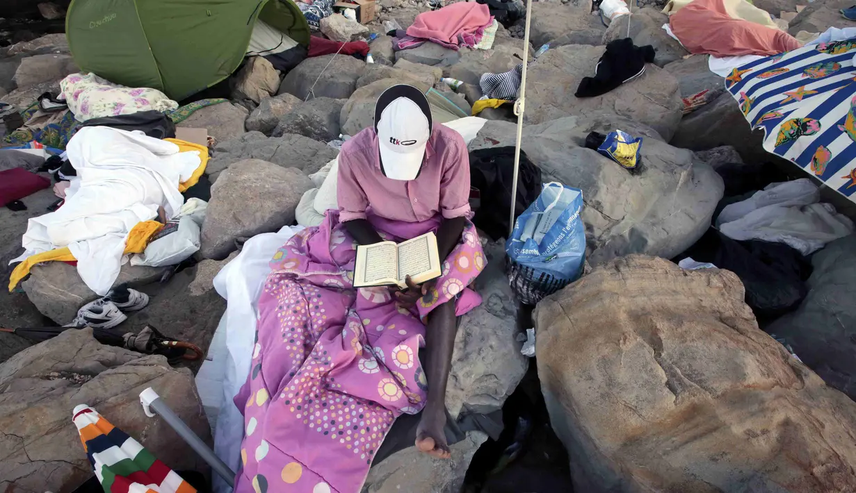 Seorang imigran membaca Al-Quran saat bulan suci ramadan di atas bebatuan laut Ventimiglia, perbatasan antara Italia-Prancis, (18/6/2015). Sekitar 200 imigran asal Eritrea dan Sudan berusaha memasuki perbatasan Italia. (REUTERS/Eric Gaillard)