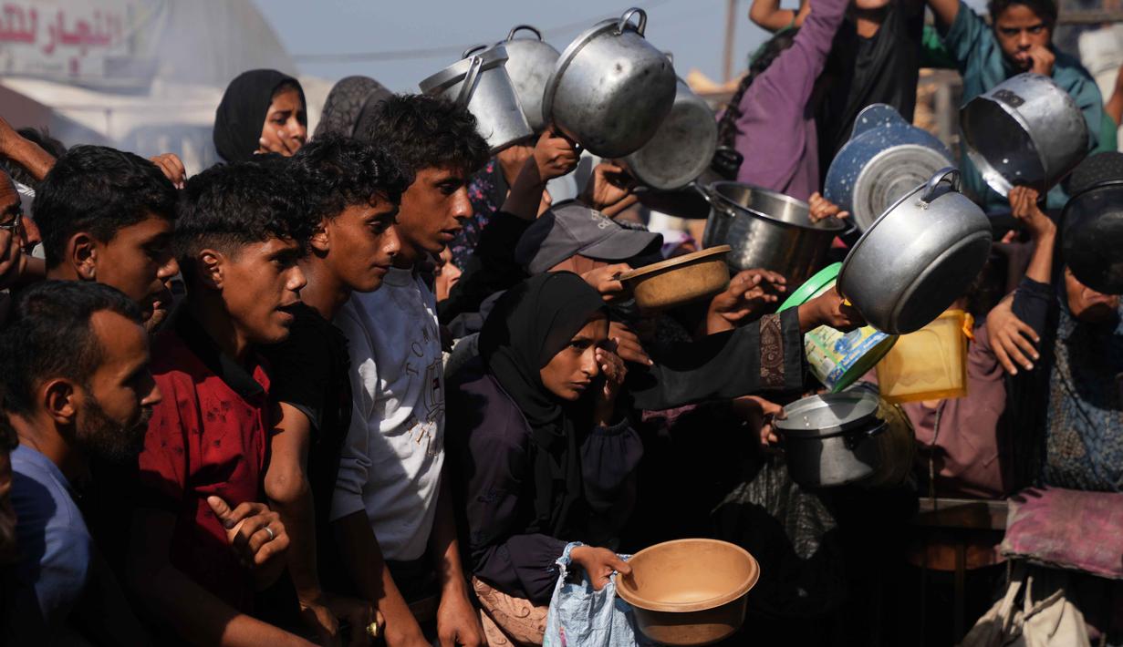 Warga Palestina menunggu bantuan gula dan beras di dapur umum di Khan Younis, Jalur Gaza selatan, Jumat, 31 Oktober 2025. Mereka datang dengan membawa panci dan piring kosong serta harapan mendapat bantuan makanan. (AP Photo/Abdel Kareem Hana)