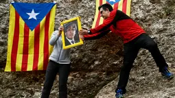 Pengunjuk rasa membawa foto presiden terguling Catalonia, Carles Puigdemont di Gunung Montserrat, Spanyol (28/4). Pegunungan Montserrat merupakan pegunungan suci yang menjadi destinasi ziarah paling terkenal bagi umat Katolik. (AFP/Pau Barrena)