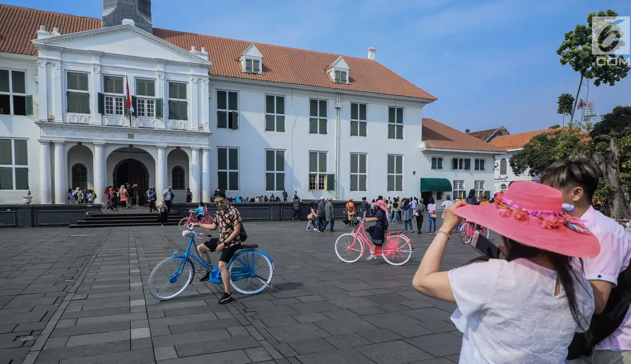 <p>Wisatawan berfoto dengan latar belakang Museum Fatahillah di kawasan Kota Tua, Jakarta, Sabtu (8/6/2019). Selama libur lebaran 2019, jam berkunjung ke berbagai museum di kawasan wisata sejarah Kota Tua diperpanjang hingga pukul 20.00 WIB. (Liputan6.com/Faizal Fanani)</p>