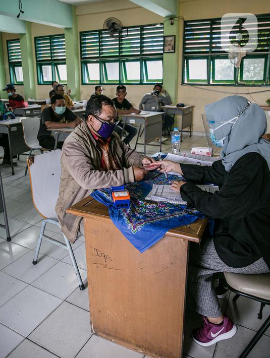 Warga mengisi data untuk mengambil Bantuan Sosial Tunai (BST) di SMAN 111, Jakarta, Selasa (19/1/2021). Pemprov DKI Jakarta menyalurkan BST sebesar Rp 300 ribu kepada 1.055.216 KK mulai Januari hingga April 2021. (Liputan6.com/Faizal Fanani)