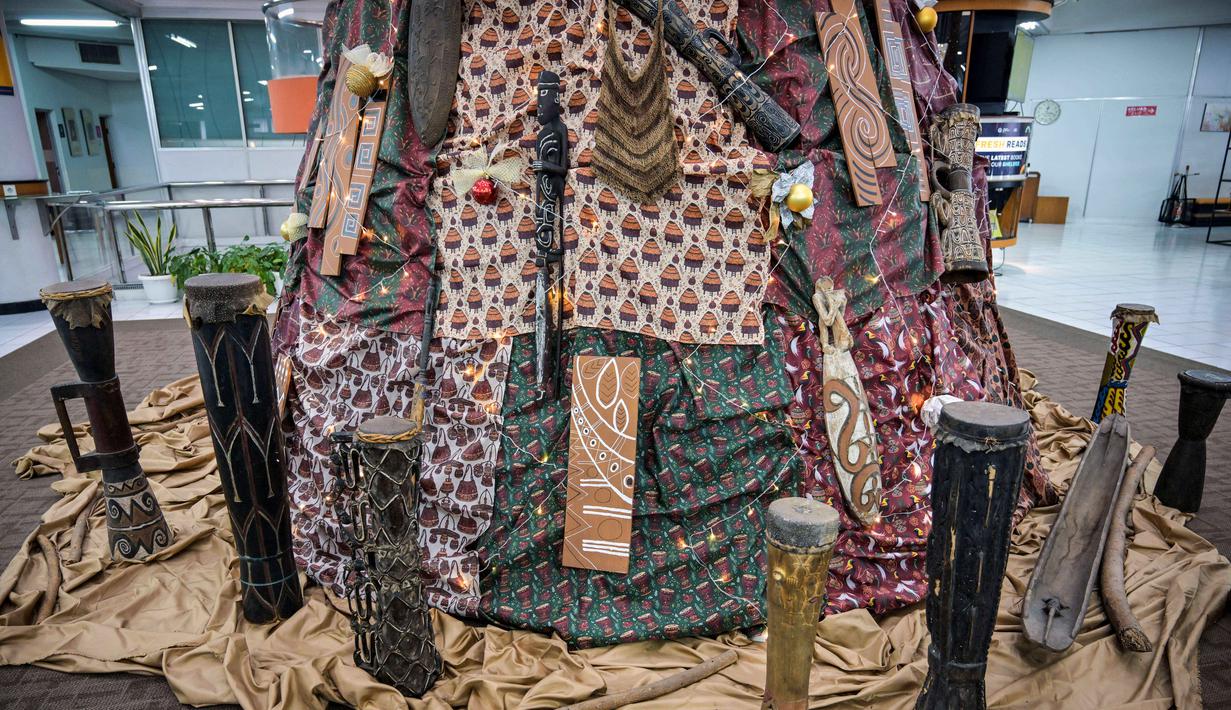 Tidak sekadar dekorasi musiman, karya ini dirancang sebagai representasi budaya sekaligus refleksi nilai spiritual Natal yang sarat makna.Tampak dalam foto, sebuah instalasi dekorasi berbentuk pohon Natal terpasang dengan motif budaya Papua di Perpustakaan Petra Christian University (PCU), Surabaya, Jawa Timur, Kamis 18 Desember 2025. (JUNI KRISWANTO/AFP)