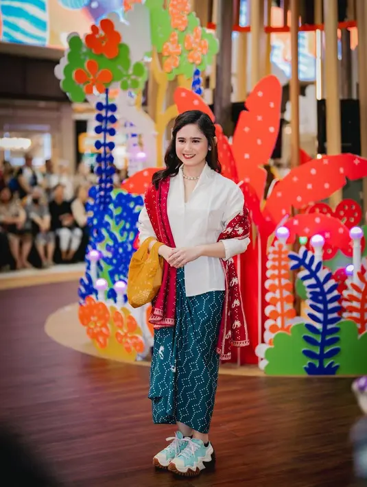 Tissa Biani tampil chic dengan kebaya klasik putih, kain bernuansa hijau kebiruan, dan selendang merah yang kontras namun serasi. [Foto: Instagram/tissabiani]