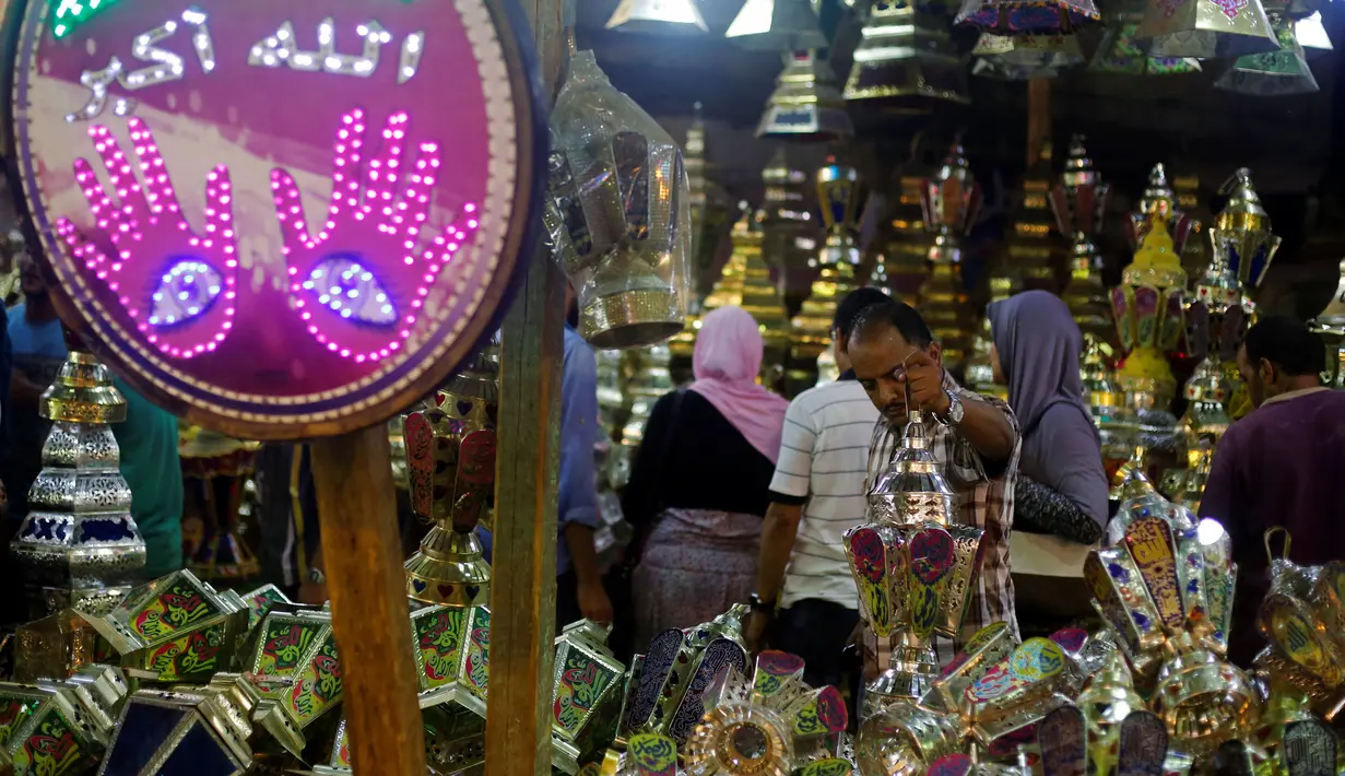 Calon pembeli saat melihat - lihat kios yang berjualan lentera khas Ramadan dan beraneka lampu di pasar Sayida Zienab, Mesir 6 Juni 2016. Lentera yang dijual beraneka ragam dengan kaligrafi Arab yang menawan. (REUTERS / Amr Abdallah Dalsh)