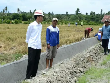 Presiden Joko Widodo berbincang dengan Menteri PUPR Basuki Hadimuljono (kanan) dan pekerja saat meninjua meninjau irigasi di Desa Waimital, Kecamatan Kairatu, Kabupaten Seram Bagian Barat (14/2). (Liputan6.com/Pool/Biro Pers Setpres)