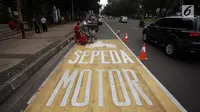 Pekerja menyelesaikan pengecatan rambu jalur kuning khusus sepeda motor di Jalan Medan Merdeka, Jakarta, Selasa (16/1).  Seperti diketahui, Mahkamah Agung (MA) membatalkan pergub larangan sepeda motor melintas di kawasan itu. (Liputan6.com/Arya Manggala)