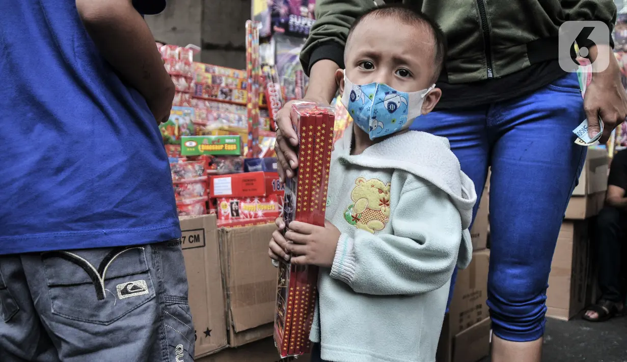 Seorang anak membeli kembang api yang dijual di Pasar Asemka, Jakarta, Selasa (28/12/2021). Pedagang di Pasar Asemka pun mengaku penjualan petasan dan kembang api saat ini mengalami penurunan. (merdeka.com/Iqbal S Nugroho)