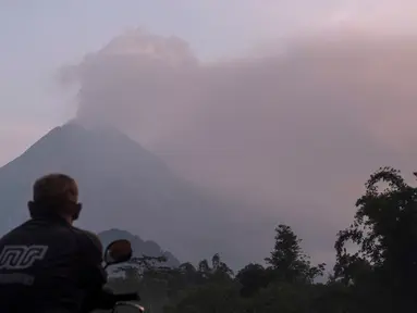 Seorang pria menyaksikan Gunung Merapi menyemburkan material vulkanik ke udara di Sleman, DI Yogyakarta, Selasa (3/3/2020). Gunung Merapi meletus pada pukul 05.22 WIB dengan tinggi kolom 6.000 meter , status waspada (level II). (AP Photo/Slamet Riyadi)