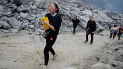 Keluarga menangis sambil membawa kertas ritual untuk menenangkan arwah orang yang tewas di lokasi tanah longsor di desa Xinmo, Sichuan, China (25/6). Sejauh ini, 15 orang telah ditemukan tewas dan puluhan rumah roboh. (AP Photo / Ng Han Guan)