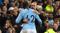 Pelatih Manchester City, Pep Guardiola, memeluk Yaya Toure usai laga melawan Brighton and Hove Albion di Stadion Etihad, Rabu (9/5/2018). Laga tersebut menjadi ajang perpisahan sang pemain bersama The Citizens. (AFP/Paul Ellis)
