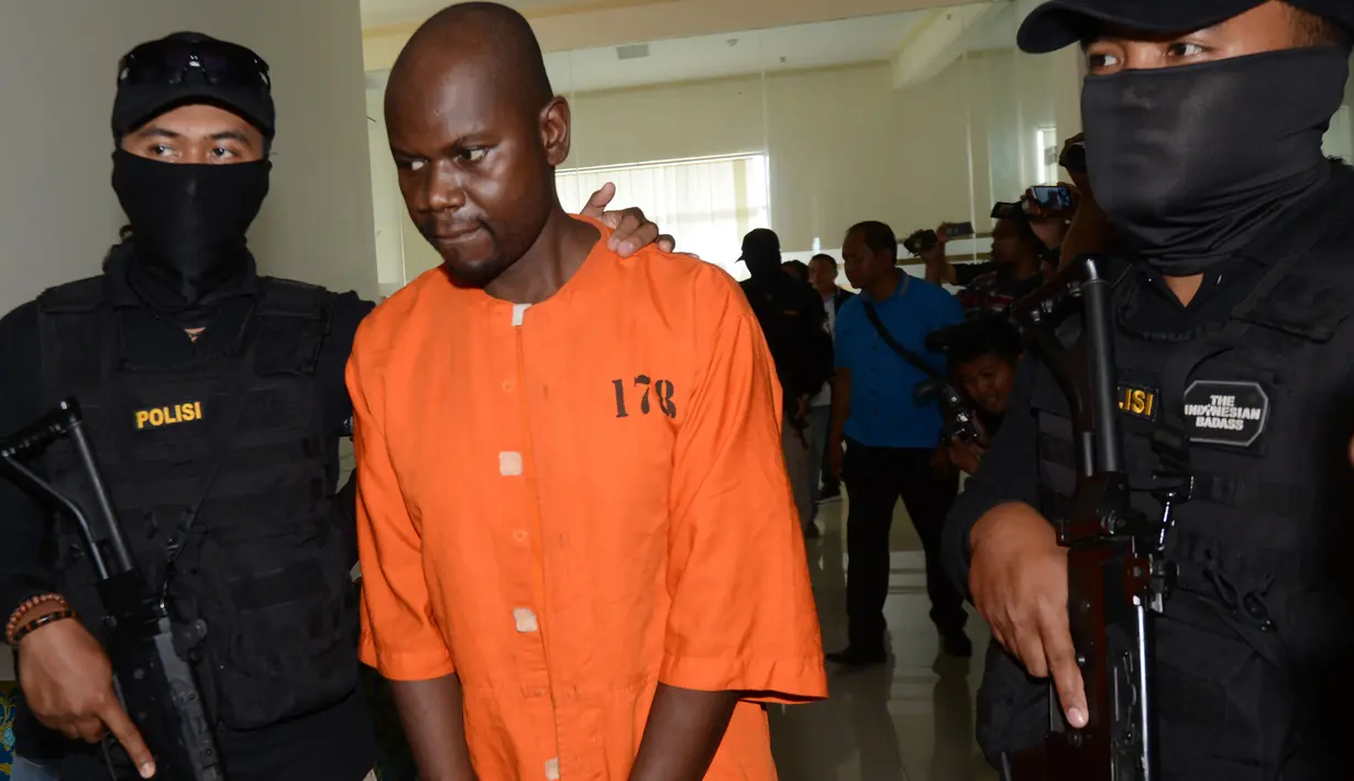 Warga Negara Tanzania, Abdul Rachman Azman dikawal petugas sebelum konferensi pers di Kantor Pelayanan Bea Cukai Bandara Ngurah Rai, Bali, Selasa (12/2). Abdul ditangkap karena menyelundupkan methamphetamine 1,13 kg di dalam perutnya (Sonny TUMBELAKA/AFP)