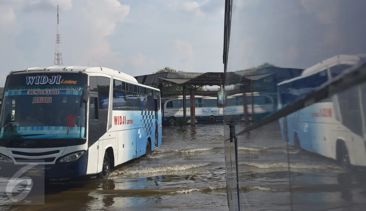 Bus melintasi banjir akibat air laut pasang atau rob yang menggenangi Terminal Terboyo di Semarang, Minggu (15/5/2016). Banjir rob tersebut mengakibatkan penumpang memilih turun di luar terminal, sehingga aktivitas di dalam terminal lumpuh. (Foto: Gholib)