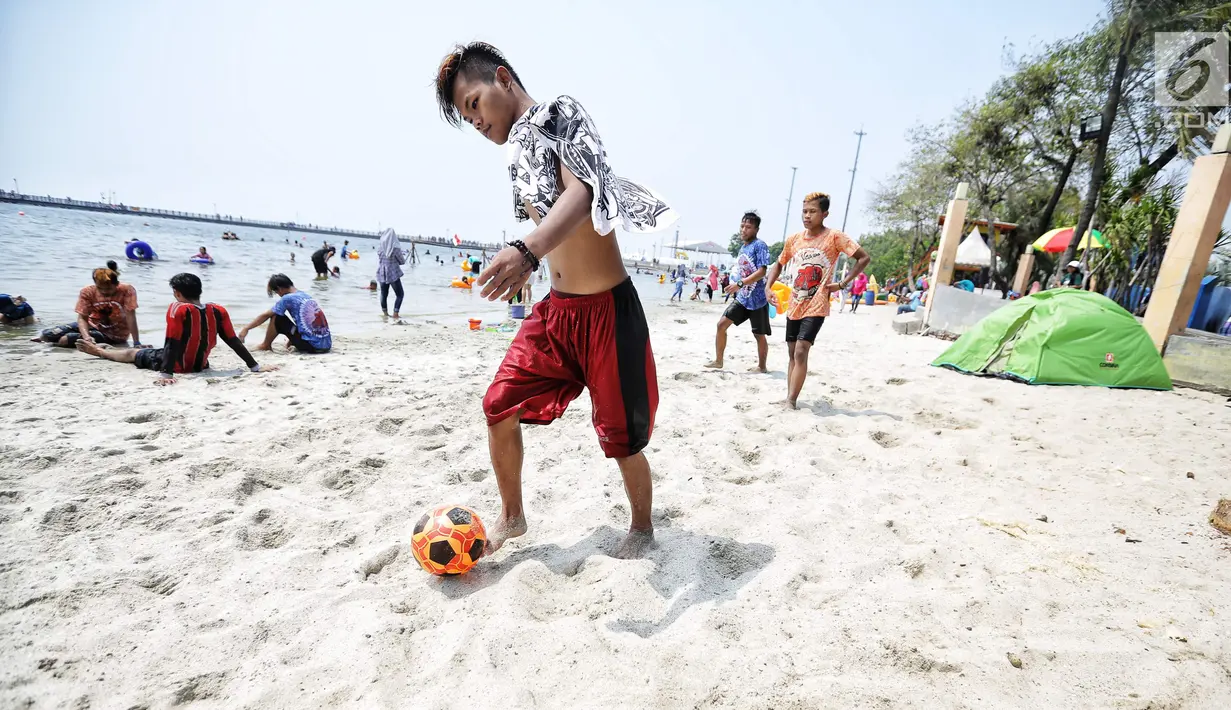 Pengunjung bermain bola di Pantai Lagoon, Ancol, Jakarta Utara, Jumat (17/8). Warga Jakarta dan sekitarnya memanfaatkan libur HUT ke-73 Republik Indonesia dengan berwisata ke kawasan Ancol. (Liputan6.com/Faizal Fanani)