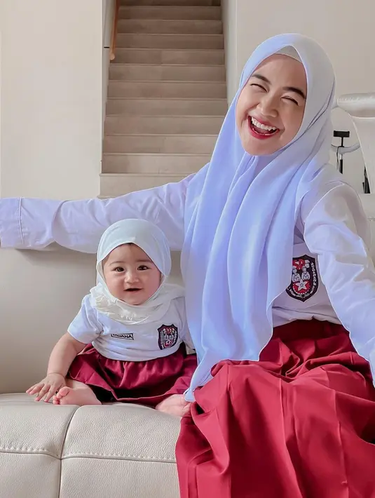 Terbaru, Ria Ricis mendandani baby Moana pakai seragam sekolah SD. Lengkap dengan hijabnya, baby Moana tampak begitu menggemaskan. Ria Ricis juga mengenakan baju yang sama dengan buah hatinya. (Liputan6.com/IG/@riaricis1795)