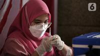 Petugas kesehatan menyiapkan vaksin booster COVID-19 di Pasar Tanah Abang Blok A, Jakarta, Senin (4/4/2022). Vaksinasi yang diselenggarakan Polri ini diikuti warga sekitar dan pedagang Pasar Tanah Abang yang berencana mudik Lebaran. (Liputan6.com/Faizal Fanani)