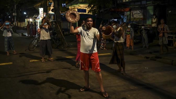Orang-orang membuat keributan dengan memukul-mukul simbal dan wajan setelah seruan untuk protes keluar di media sosial di Yangon, Myanmar, 3 Februari 2021. Kudeta militer Myanmar terus memicu protes warga dengan membunyikan klakson mobil, menyalakan lampu ponsel, dan memukul-mukul panci. (STR/AFP)