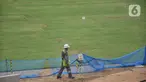 Pekerja melintas di dekat rumput hybrid Jakarta International Stadium (JIS), Selasa (26/10/2021). Jakarta International Stadium menjadi stadion pertama di Indonesia yang menggunakan rumput hybrid atau perpaduan antara rumput alami dan sintetis. (merdeka.com/Iqbal S Nugroho)