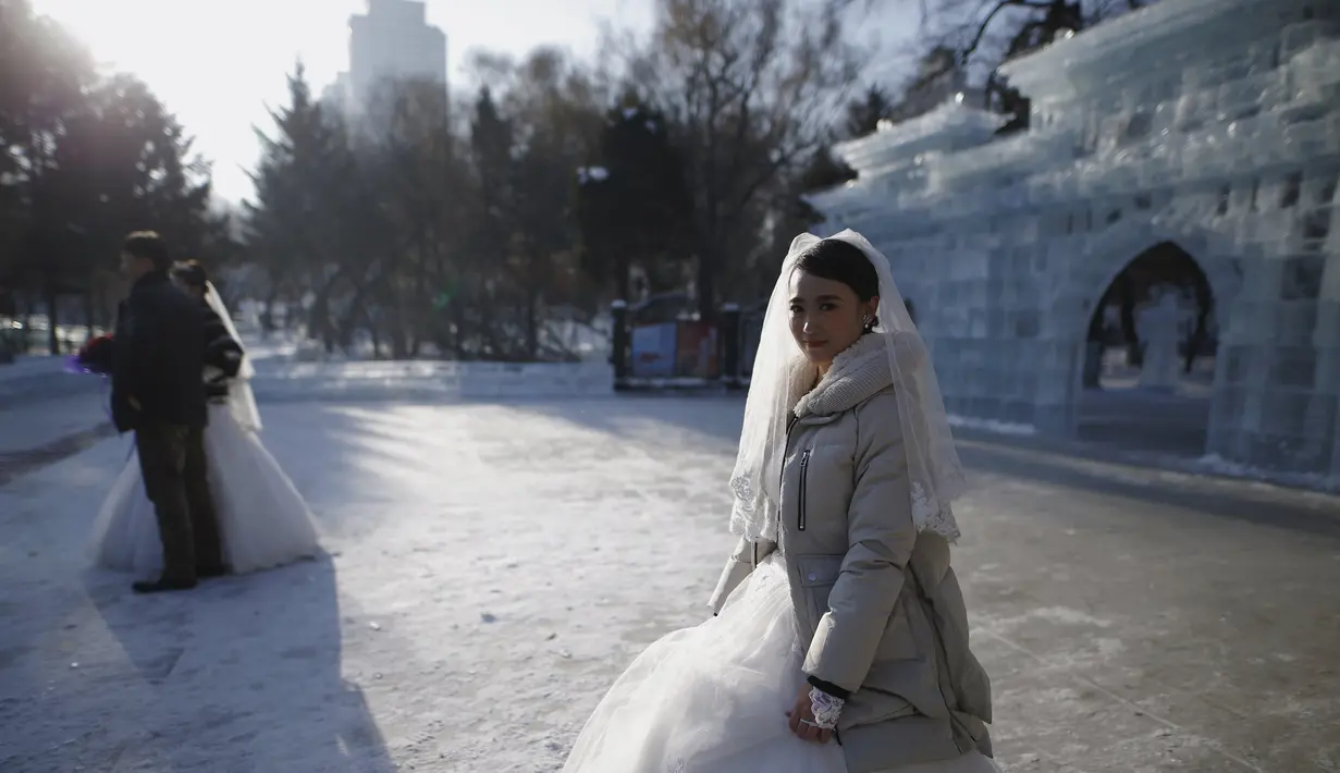 Pengantin baru menunggu giliran untuk berfoto di depan bangunan yang terbuat dari balok es usai upacara pernikahan massal yang merupakan bagian dari Festival Es dan Salju Harbin di provinsi Heilongjiang, China, Rabu (6/1/2016). ( REUTERS/ Aly Song)