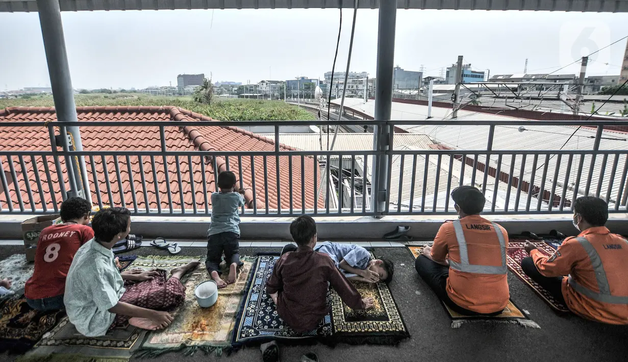 Umat Islam mendengarkan ceramah saat menunaikan salat Jumat di Stasiun Kampung Bandan, Jakarta, Jumat (7/5/2021). Sebagian jemaah menjadikan peron stasiun sebagai tempat salat dan sebagian lain berada di tangga serta jembatan penyeberangan. (merdeka.com/Iqbal S. Nugroho)