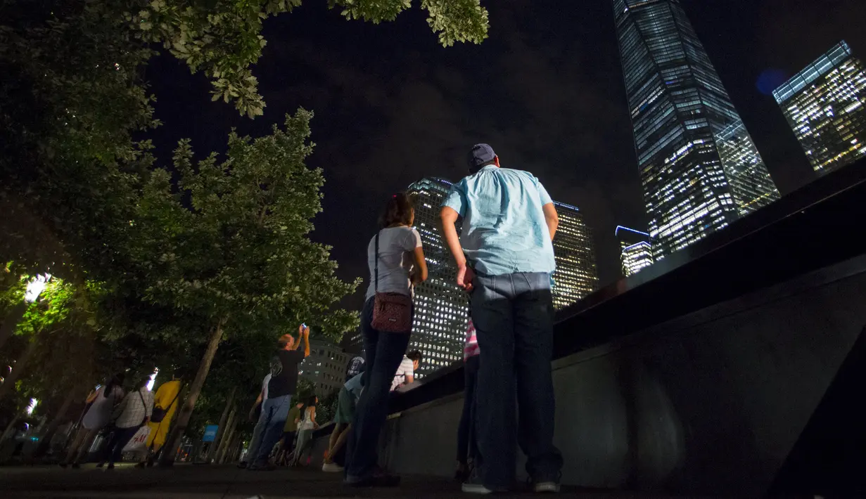 Pejalan kaki menyaksikan keindahan lampu sorot dipancarkan ke langit dari World Trade Center (WTC) kota New York, AS, (9/9/2015). Acara Tribute in Light memperingati 14 tahun tragedi terorisme 11 September di Amerika Serikat. (REUTERS/Andrew Kelly)