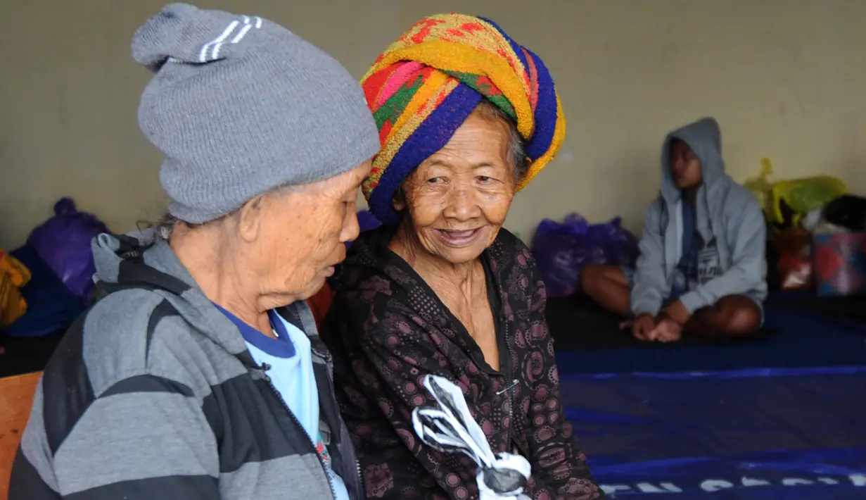 Dua orang wanita lansia berbincang usai dievakuasi di tempat penampungan sementara di Kabupaten Klungkung, Bali (22/9). Para penduduk desa dievakuasi sehubungan meningkatnya aktivitas Gunung Agung. (AFP Photo/Sonny Tumbelaka)