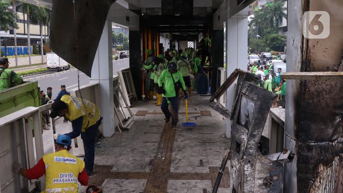 Sejumlah petugas membersihkan sisa kerusakan Halte Bus TransJakarta Tosari, Jakarta, Jumat (9/10/2020). Sejumlah fasilitas umum rusak dalam kericuhan unjuk rasa menolak pengesahan UU Cipta Kerja yang terjadi Kamis (8/10).  (Liputan6.com/Angga Yuniar)