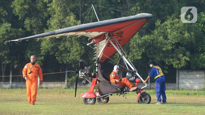 Anggota Federasi Aero Sport Indonesia (FASI) bersiap menerbangkan pesawat Microlight Trike yang membawa spanduk ucapan 