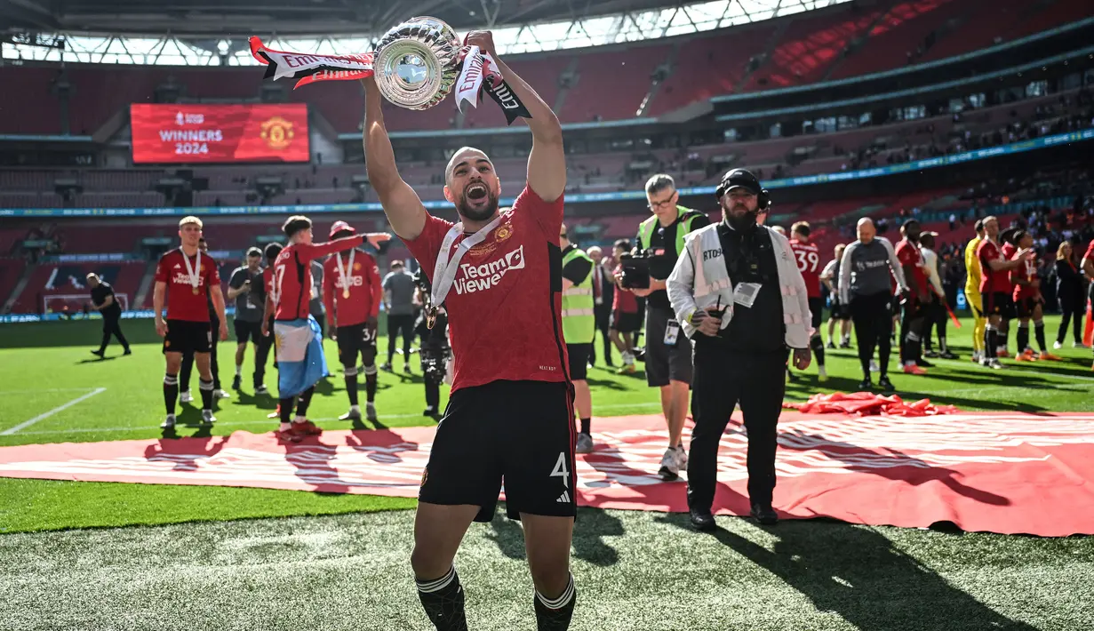Pemain Manchester United, Sofyan Amrabat merayakan gelar juara Piala FA 2023/2024 di Stadion Wembley, London, Sabtu (26/05/2024). MU menang dengan skor 2-1 atas Manchester City di partai final. (AFP/Justin Tallis)