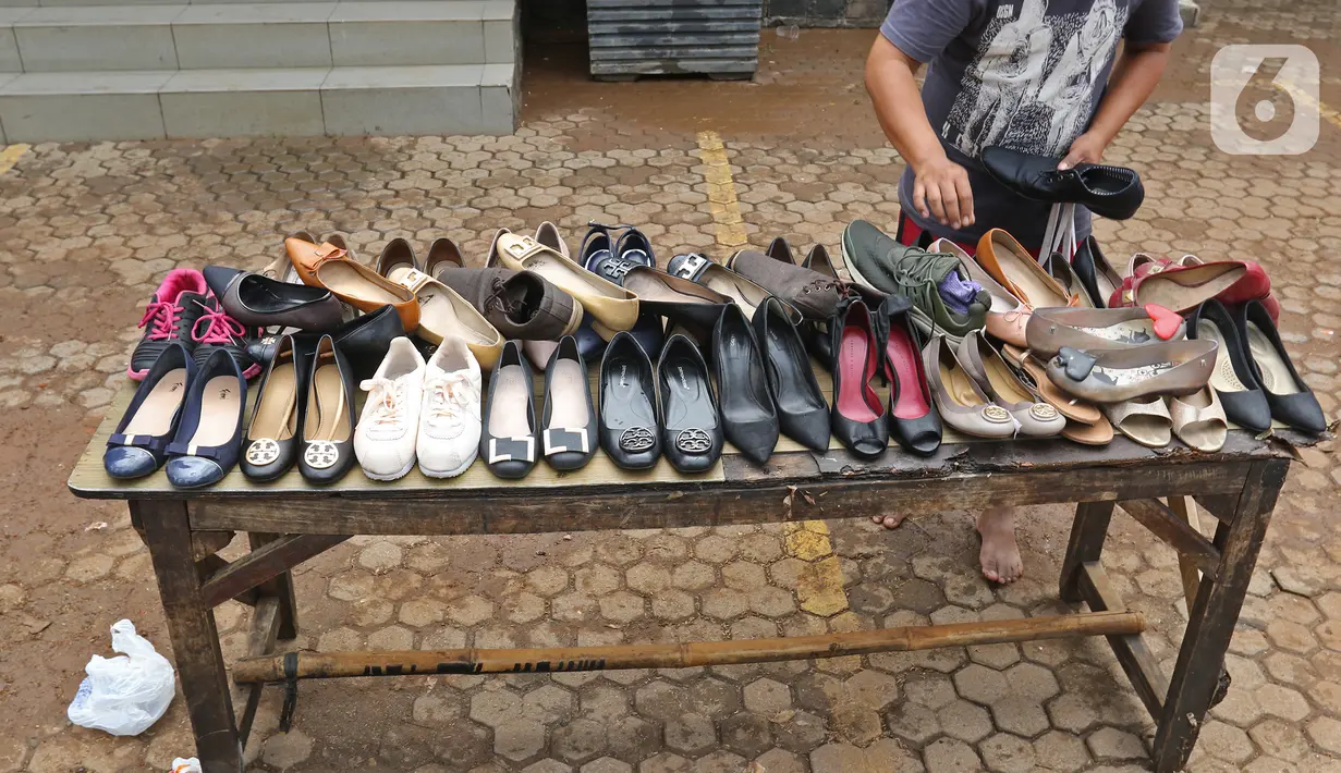 Pegawai menjemur sepatu di salah satu bank kawasan Kemang Raya, Jakarta, Kamis (2/1/2020). Para pegawai mulai membersihkan ruangan yang terendam air pascabanjir yang melanda Kemang Raya. (Liputan6.com/Herman Zakharia)