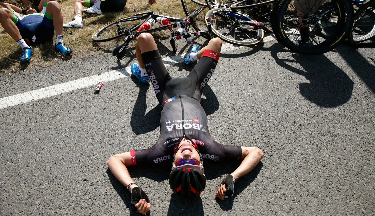 Seorang pembalap terlihat berbaring usai insiden kecelakaan yang melibatkan puluhan pebalap sepeda saat babak ketiga Tour de France dari Anvers ke Huy di Belgia, Senin (6/7/2015). (REUTERS/Eric Gaillard)
