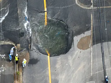 Air keluar dari retakan dan membanjiri jalan menyusul gempa bumi di Takatsuki, Osaka, Jepang, Senin (18/6). Gempa berkekuatan 6,1 SR menghantam Osaka pada Senin pagi. (Yohei/Nishimura/Kyodo News via AP)